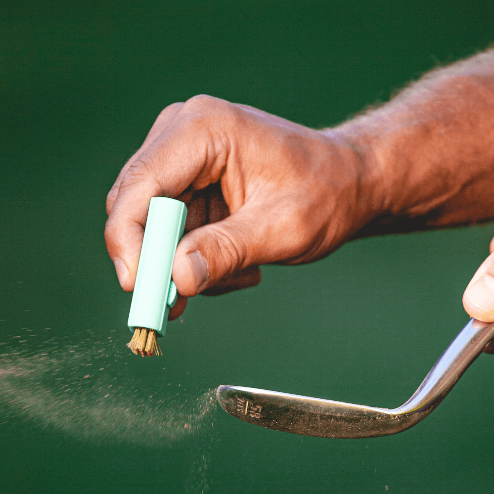 Pocket Brush golf club cleaner and groove brush cleaning the club face of a golf club