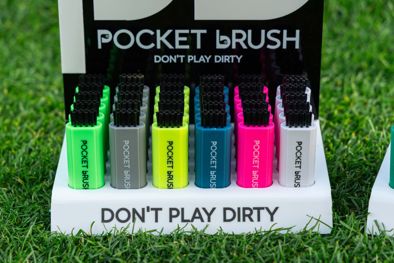 Set of colorful pocket brushes on a display stand with grass background