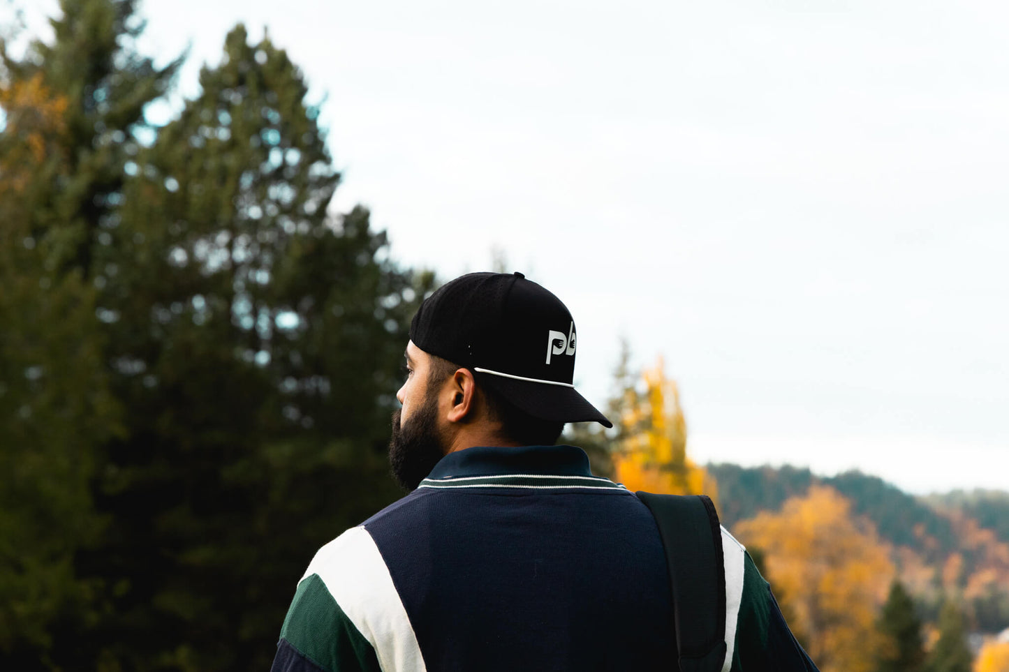 Person wearing a black pocket brush cap  in a forest setting