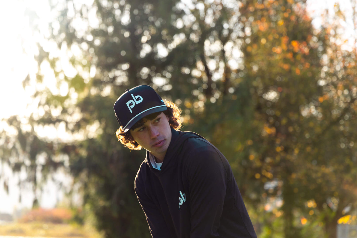 Person wearing a black cap with a Pocket Brush logo outdoors