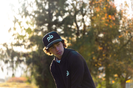 Person wearing a black cap with a Pocket Brush logo outdoors