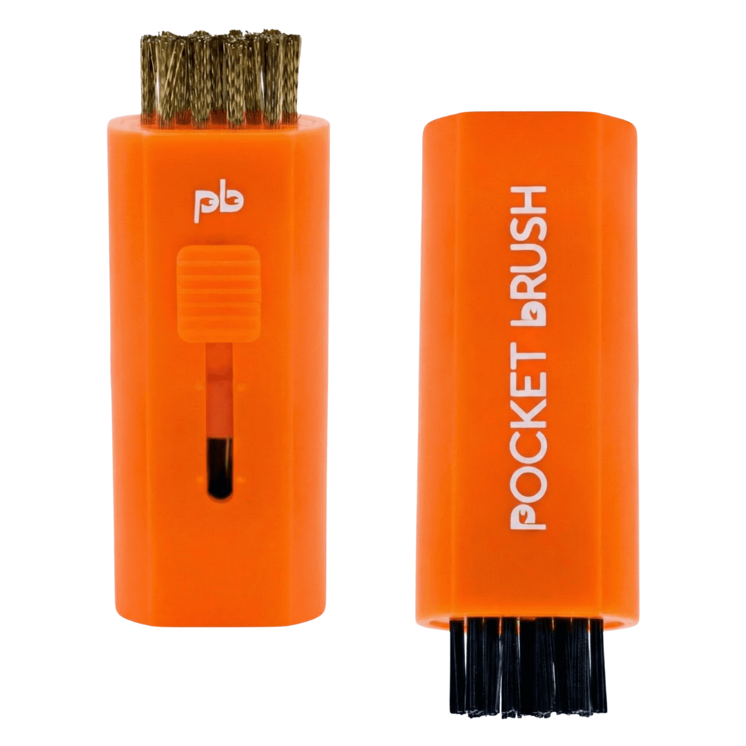 An orange Pocket Brush golf club brush and groove cleaner with both the brass and nylon bristles exposed lies on a white background.