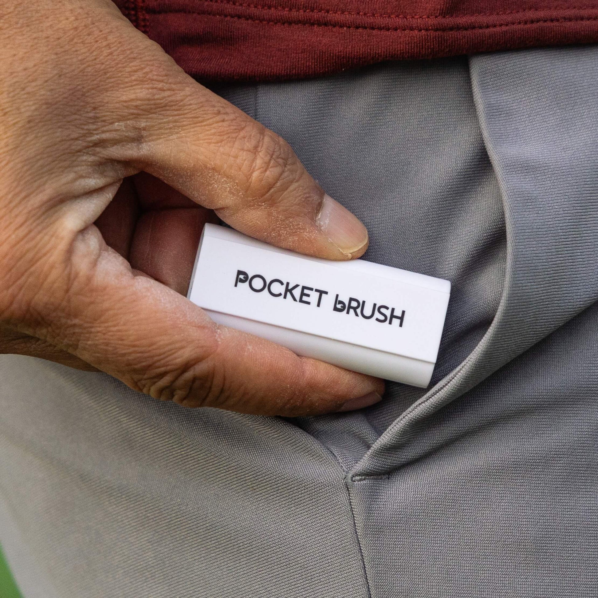 A white Pocket Brush is being inserted into a grey pant pocket