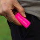A bright pink Pocket Brush is being inserted into a black pants pocket