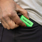A neon green Pocket Brush is being held next to black pant pocket