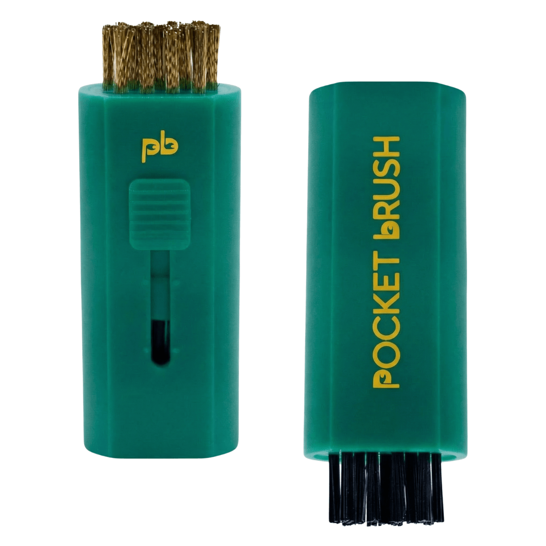 A masters green Pocket Brush golf club brush and groove cleaner with both the brass and nylon bristles exposed lies on a white background.