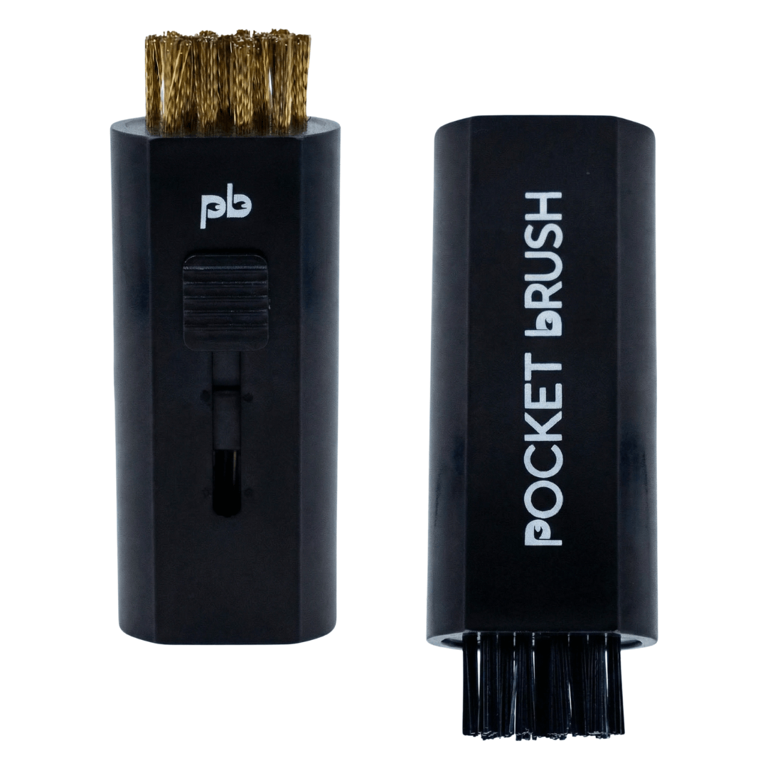 A black Pocket Brush golf club brush and groove cleaner with both the brass and nylon bristles exposed lies on a white background.