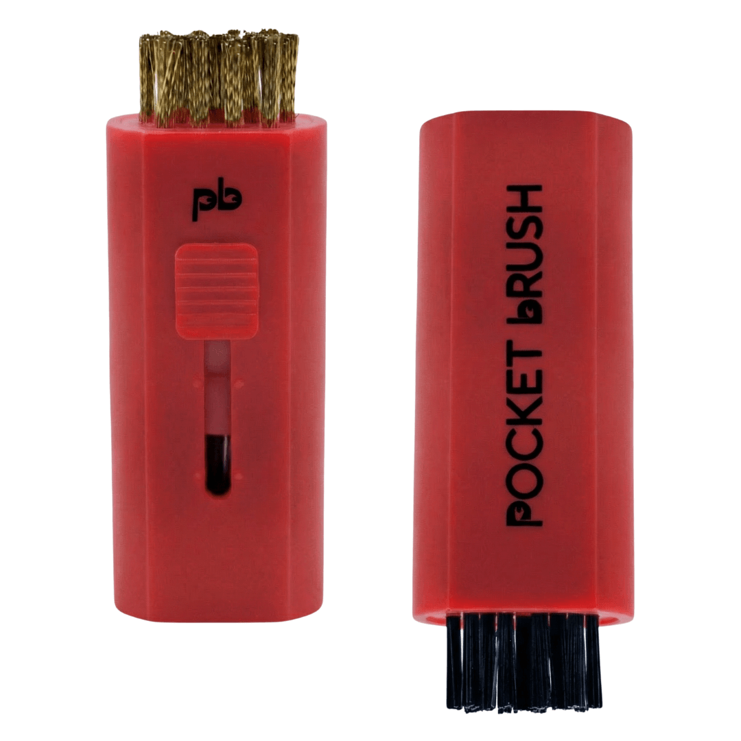A red Pocket Brush golf club brush and groove cleaner with both the brass and nylon bristles exposed lies on a white background.