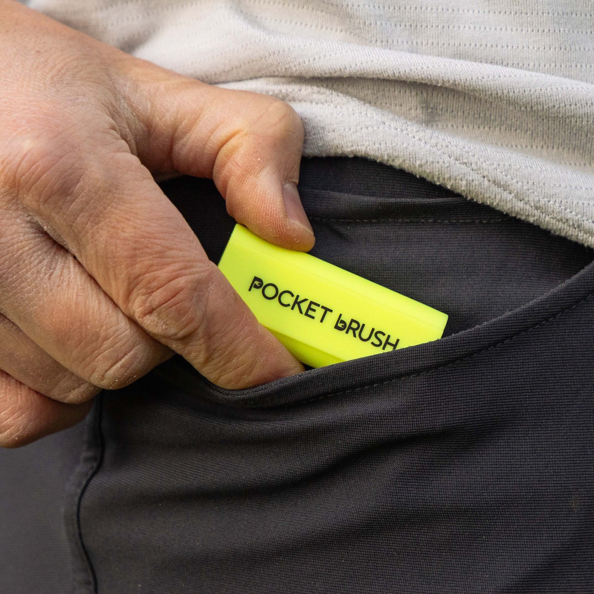 A neon yellow pocket brush is being placed into a pocket