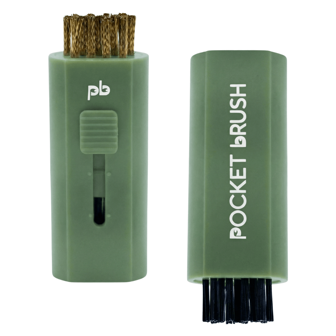 A sage green Pocket Brush golf club brush and groove cleaner with both the brass and nylon bristles exposed lies on a white background.