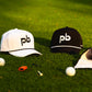 Two caps with 'Pocket Brush' logo on a grassy surface