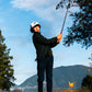 Person playing golf wearing a white pocket brush cap with mountains and trees in the background